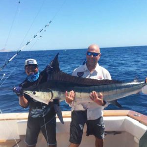 Two men hoisting up a fish they caught